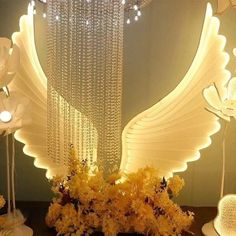 an arrangement of flowers and lights in the shape of angel wings