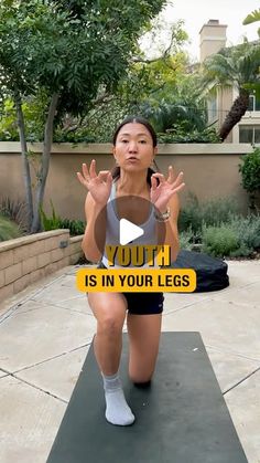 a woman in grey shirt and black shorts doing yoga with her hands up to the side