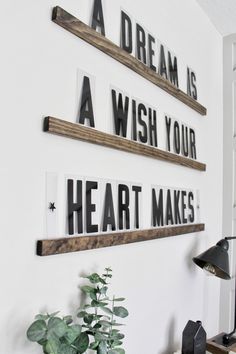 three wooden shelves are hanging on the wall above a desk with a potted plant