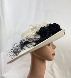 This unique shape wide-brimmed telescope wool felt hat would be perfect for any special occasion. The hat is trimmed with Ivory and black assorted velvet flowers, a black grosgrain ribbon band, and black netting that is removable. The hat will fit up to a 22 5/8 inch head size with an inside sizing ribbon. White Brimmed Felt Hat For Kentucky Derby, White Fitted Felt Hat With Curved Brim, White Flat Brim Hats For Formal Occasions, White Brimmed Felt Hat For Formal Occasions, Fitted White Felt Hat With Wide Brim, White Wide Brim Felt Hat For Formal Occasions, Fitted White Wide Brim Felt Hat, White Fitted Wide Brim Felt Hat, White Brimmed Felt Hat For Party