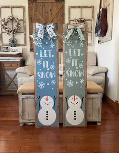 two snowmen standing next to each other in front of a wooden sign that says let it snow