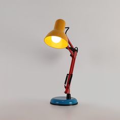 a red desk lamp with a yellow light on it's side and a blue base