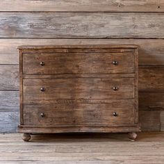 an old wooden chest of drawers against a wood wall