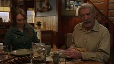 an older man and woman sitting at a table