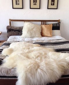 a white sheepskin rug on top of a bed with two framed pictures above it