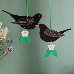 two black birds hanging from strings with flowers