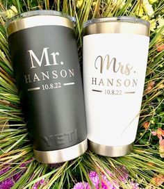 two personalized tumblers sitting next to each other on some grass with flowers in the background