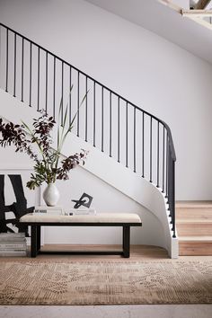 a vase with flowers on a table in front of a stair case and coffee table