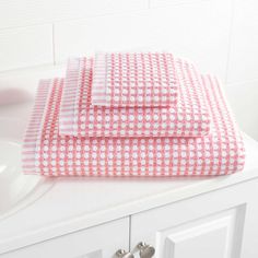 two pink and white towels sitting on top of a bathroom counter next to a sink