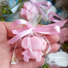 a hand holding a small pink soap in a clear bag with a ribbon around it