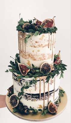 a three tiered cake decorated with figs and greenery