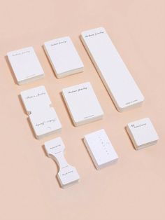 six white business cards are arranged next to each other on a light pink surface,