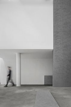 a blurry photo of a person walking in an empty room with concrete walls and floors