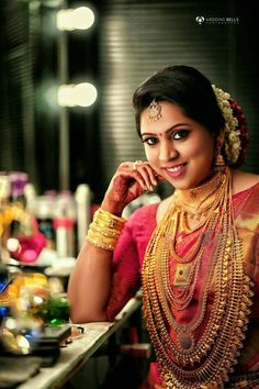 a woman in a red and gold sari posing for the camera with her hand on her chin