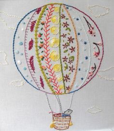 an embroideryed hot air balloon with flowers on it's side and a basket in the middle