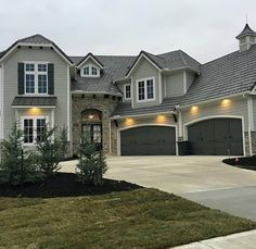 a large house with two garages and lights on the front door is pictured in this image