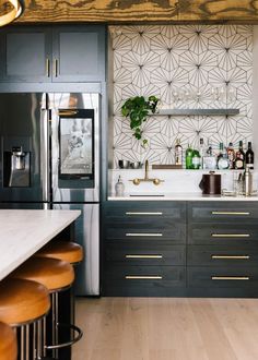 a kitchen with black cabinets and white counter tops, gold accents on the backsplash