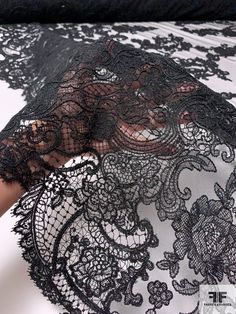 a woman's hand holding an umbrella covered in black lace