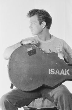 a man sitting on a stool holding an acoustic guitar