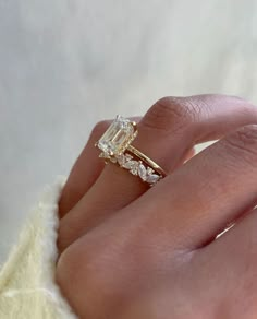 a woman's hand with a diamond ring on top of her finger and an engagement band