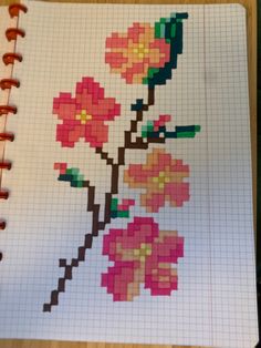 a cross stitched notebook with flowers on the page and colored pencils next to it