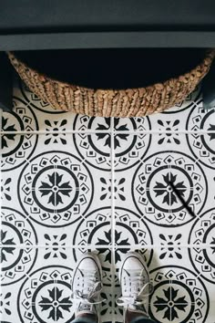 someone is standing on the floor with their feet up in front of a black and white tile