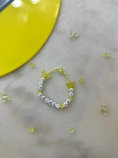 a bracelet with beads sits on a table next to a yellow paddle and some confetti