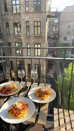 three plates of spaghetti and wine on a balcony