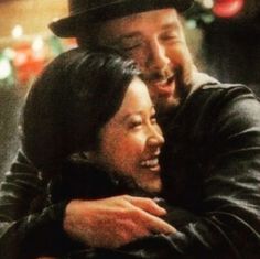 a man and woman embracing each other in front of a christmas tree