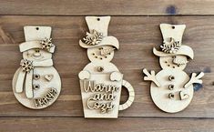 three wooden snowmen with hats and scarfs hanging from the side on a wood background