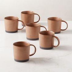 four coffee mugs sitting next to each other on a white counter top with one cup in the middle