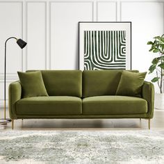 a green couch sitting on top of a wooden floor next to a lamp and rug