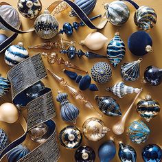 an assortment of blue and white ornaments on a gold table top, including one large ornament