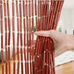 a hand is holding some red sticks in front of a white wall and wooden floor