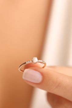 a woman's hand holding a ring with a pearl and diamond on the side