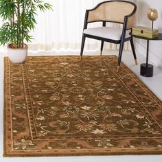 a chair and table in a room with a large rug on the floor next to a potted plant