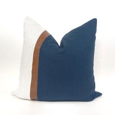 a blue and white pillow with two brown stripes on it's side, sitting against a white background