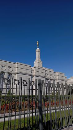 a tall building with a clock tower on top of it's side next to a fence