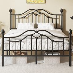 a black metal bed frame with white sheets and pillows on it in a room that has carpeted flooring