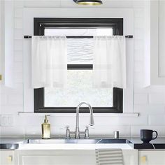 a kitchen sink under a window with white curtains