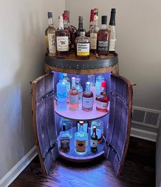 a wooden barrel filled with liquor bottles on top of a table next to a wall