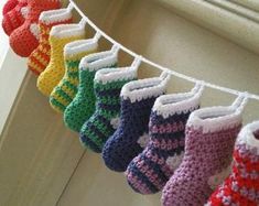 colorful knitted baby booties hanging on a clothes line in front of a window