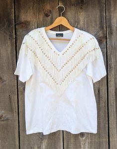 Super cute white bedazzled t shirt, 1980s vintage. Features a white cotton/poly blend, V neckline, loose boxy fit, layered fringe chest decoration with multiple stripes of gold studs & rhinestones, and lots of retro western glamour... Perfect as casual glam rock, or square dancing attire...;) Brand : Clodia Dee Made in the USA 50% cotton, 50% polyester No size labeled, fits like a L All measurements taken with garment lying flat, double where necessary roughly 18 inches shoulder to shoulder 23 i Fringe T Shirt, Fringe Tshirt, Layered Fringe, Western Glam, Rhinestone Cowgirl, September 28th, Casual Glam, Retro Western, Square Dancing