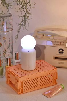 an electronic device sitting on top of a table next to a vase with flowers in it