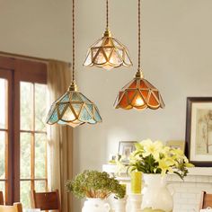 three lights hanging from the ceiling above a dining room table with flowers in vases