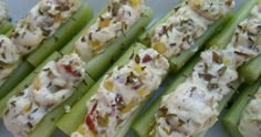 celery sticks with various toppings on them sitting on a white plate, ready to be eaten