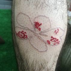 a close up of a person's leg with tattoos on it and words written in red ink