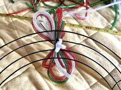 several pieces of string tied together on top of a bed next to a measuring tape