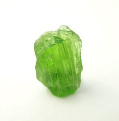 a green rock sitting on top of a white surface