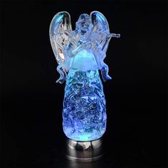 an illuminated glass angel figurine on a metal base with blue light in the dark